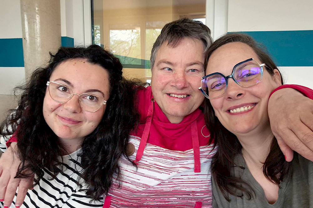 Image shows three people hugging each other.