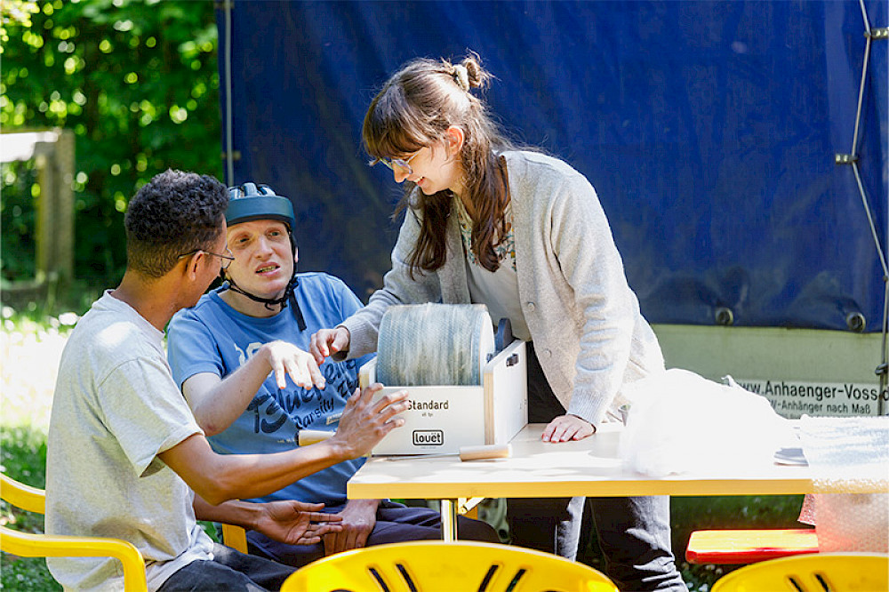 Bild zeigt drei Personen bei einem Sommerfest.