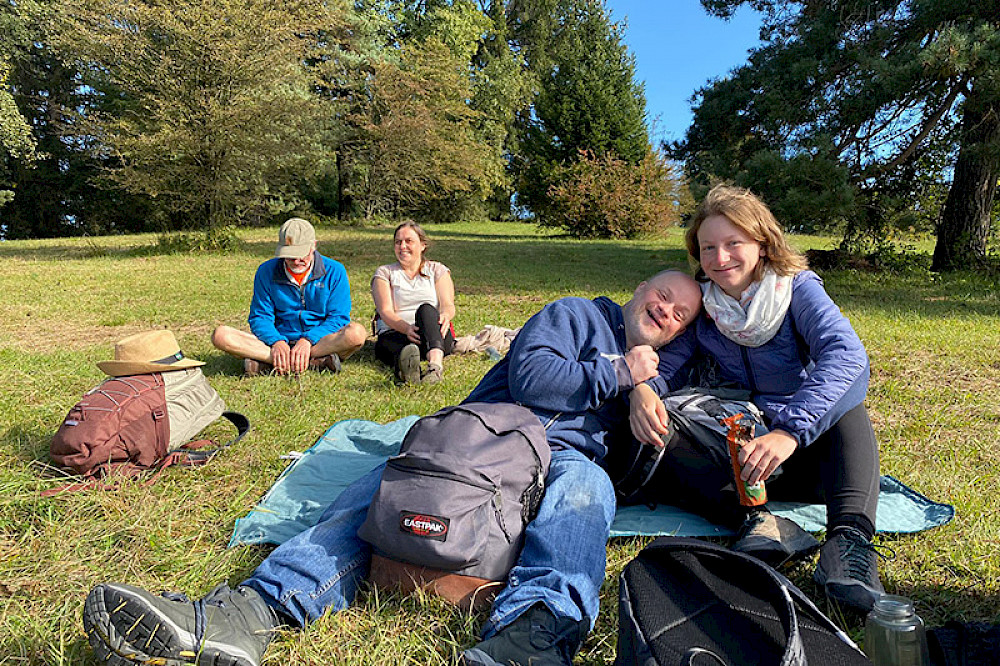 Bild zeigt Personen auf einer Wiese bei einer Wanderrast.