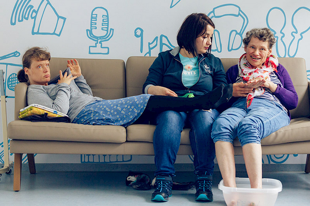 Bild zeigt drei Personen auf einem Sofa.