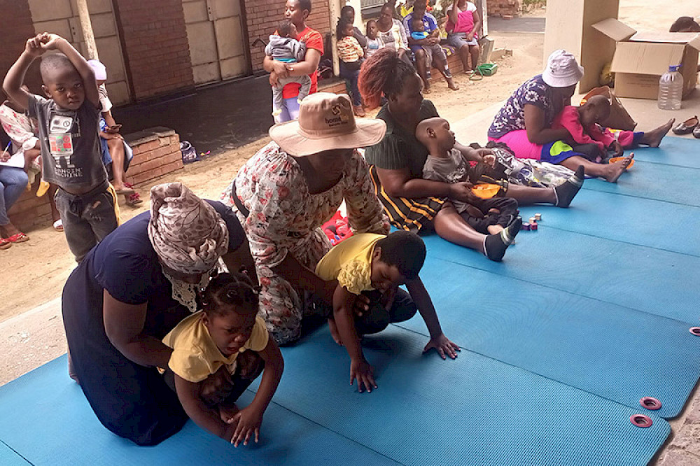 Bild zeigt Eltern mit Kindern in Simbabwe beim therapeutischen Training.